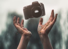 Hands tossing a DSLR camera with a magical sparkle effect in nature.